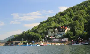 Malowniczy zbiornik wodny z zaporą, budynkami hotelowymi na zboczu góry i łodziami przy brzegu.