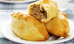 Złociste pierogi litewskie, jeden przekrojony, odsłaniający sycące mięsne nadzienie. Pyszna przekąska na talerzu.