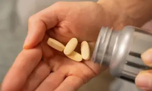 Dłoń z kilkoma tabletkami witaminy B12. Czy witamina B12 jest szkodliwa? Zazwyczaj nie, ale warto znać dawkowanie.