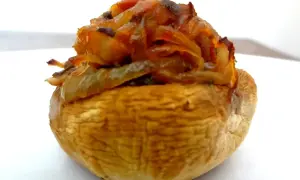 Gros plan sur un champignon farci, garni d'oignons caramélisés et d'herbes. Un délice à savourer !