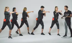 Grupa osób w strojach EMS ćwiczy pod okiem trenera. Dowiedz się, ile kosztuje trening EMS i zacznij swoją metamorfozę!