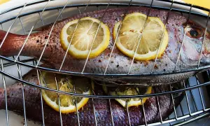 Två hela, kryddade fiskar med citronskivor på, redo att grillas. En härlig vit fisk för en sommarkväll.