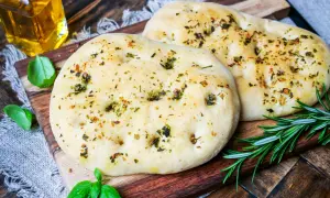 Zwei knusprige pizzabrote mit knoblauch und Kräutern, garniert mit frischem Rosmarin und Basilikum.