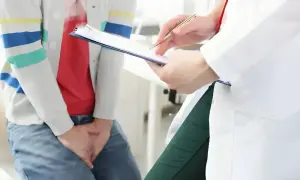 Pacjent rozmawia z lekarzem o tym, jak dostać się do urologa. Lekarz zapisuje coś na kartce.
