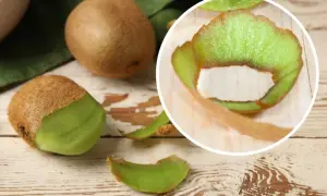 Kiwi ze skórką, częściowo obrane, leżą na drewnianym blacie. W okręgu widać zieloną skórkę kiwi.