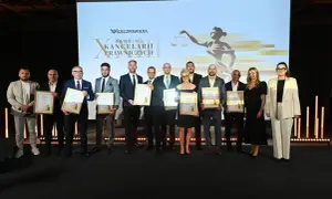 Grupa osób w garniturach i sukience odbiera nagrody na scenie przed ekranem z logo "Rzeczpospolita".