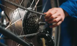 Ręka reguluje przerzutki w rowerze, poprawiając płynność jazdy. Widoczna kaseta Shimano i przerzutka.