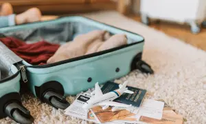 Otwarta walizka z ubraniami, obok paszport, bilety i model samolotu. Gotowy do podróży z Electra Airways bagaż.