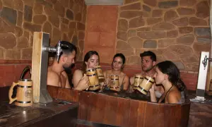 Amigos disfrutan de un relajante spa de cerveza en Valencia, brindando con jarras de madera.