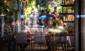 Ludzie siedzą przy stole w restauracji Olivia Business Centre, pijąc i rozmawiając.