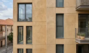Fachada moderna con textura de arena, ventanas oscuras y balcones. El mejor mortero para fachadas exteriores protege esta construcción.