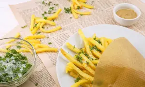 Des frites dorées, saupoudrées de persil et de sel, servies dans un cornet en papier. À côté, un bol de sel et de persil, et une petite coupelle de moutarde. Un délice qui rappelle les sardines frites.
