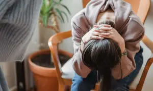 En person sitter med huvudet i händerna, kanske överväger effekterna av anafranil och alkohol.