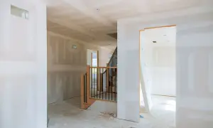 Interno in costruzione, con pareti in cartongesso grezzo e una scala. Ideale per chi cerca come realizzare una parete divisoria economica.