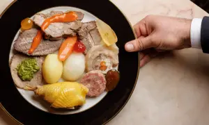 Un piatto ricco di bollito di carne, con verdure, salumi e un pollo arrosto, pronto per essere gustato.