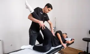 Un kinésithérapeute aide une patiente à faire un exercice pour soulager une **douleur à la hanche**.