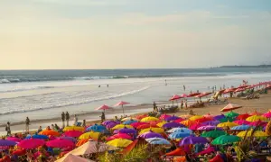 Kolorowa plaża na Bali, pełna parasoli i ludzi relaksujących się na leżakach. Idealne miejsce na wakacje.