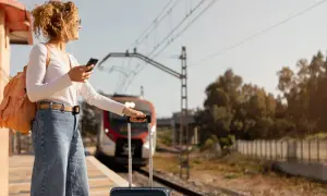 Kobieta z plecakiem i walizką czeka na pociąg PKP. Jej bagaż ponadwymiarowy jest gotowy do podróży.