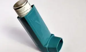 Inhalator Ventolin w kolorze turkusowym na białym tle.
