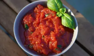 Schüssel mit frischer, stückiger Tomatensoße, wie in der Pizzeria, garniert mit Basilikum. Perfekt für hausgemachte Pizza.