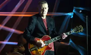 Mężczyzna gra na gitarze, przypominając styl The Beatles "Let It Be (Remastered 2009)".