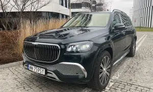 Elegancki, czarny GLS Maybach lśni na tle nowoczesnej architektury.