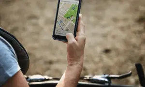 Rowerzysta sprawdza na telefonie mapę z trasą. Lokalizator GPS do roweru pomaga znaleźć drogę.