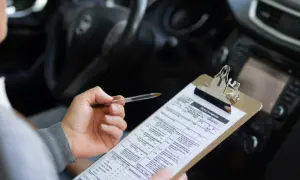 Persona revisa un formulario de solicitud de examen de manejo, preparándose para obtener su carnet coche automático.
