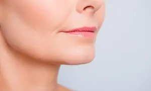 Primer plano de labios rosados y piel con un ligero surco nasogeniano, mostrando detalles de la textura facial.