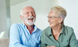 Szczęśliwi seniorzy śmieją się, omawiając zwrot podatku od 13 i 14 emerytury w tabeli.