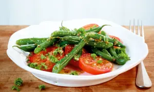 Frischer Bohnen Tomaten Salat mit Kräutern und einer leichten Vinaigrette, serviert auf einem weißen Teller.
