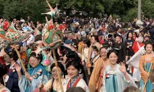 Bunte Drachenköpfe und Menschen in traditionellen Gewändern beleben den **Carnival Berlin**. Eine fröhliche Parade zieht durch die Menge.