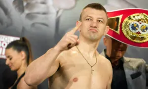 Adamek, znany z kariery bokserskiej, pokazuje swój pas mistrzowski, gotowy na walkę w świecie fame MMA.