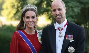 Kate i William w królewskich strojach, z diademem i medalami, uśmiechają się do zdjęcia.