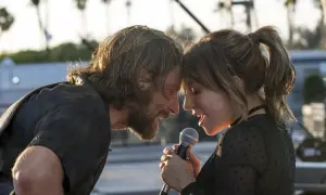 Bradley Cooper i Lady Gaga śpiewają razem, zbliżając twarze do mikrofonu.