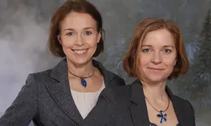 Två kvinnor, en av dem Anna Borgeryd, ler mot kameran i en studiobild med vintertema.