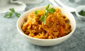 Pyszny bigos z białej kapusty, duszony z marchewką i przyprawami, udekorowany natką pietruszki.