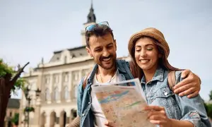 Uśmiechnięta para planuje wyjazd na weekend, studiując mapę na tle zabytkowej architektury.