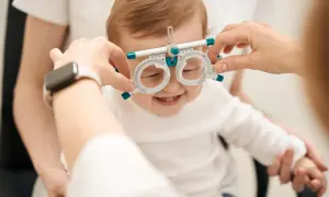 Uśmiechnięte niemowlę z oprawką optometryczną na nosie, jak widzi miesięczne dziecko.