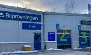Bilprovningen med entré och garageportar för besiktning. En varningstriangel syns inte, men bilen är redo för kontroll.