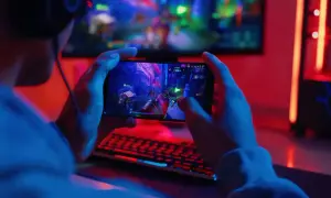 Gracz trzyma smartfon z grą akcji, odkrywając możliwości zarabiania na graniu w gry.