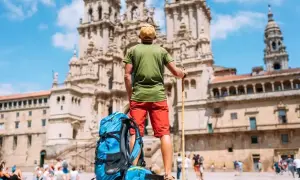 Pielgrzym z plecakiem i laską przed katedrą w Santiago de Compostela. Święta w El Camino to cel podróży.