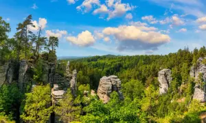Felsformationen und grüne Wälder laden zum tschechien wandern ein. Ein malerischer Ausblick unter blauem Himmel mit Wolken.