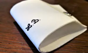 Un dettaglio di una camicia bianca piegata, con le iniziali "F.B." ricamate in nero.