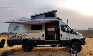 Ce **modèle camion** Iveco Daily aménagé pour le "Van Life Adventure" est prêt pour l'exploration, avec son toit relevable et son auvent déployé.