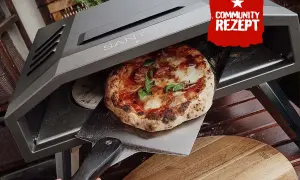 Eine frisch gebackene Pizza wird aus einem Santos Pizzaofen auf eine Pizzaschaufel gehoben.