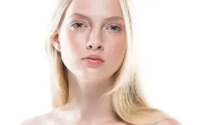 Młoda kobieta o jasnej cerze i blond włosach, uosobienie skandynawskiej urody. Delikatne rysy twarzy, błękitne oczy i subtelny rumieniec.