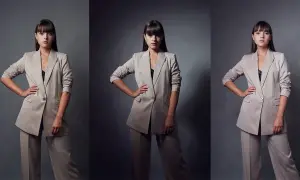 Kobieta w beżowym garniturze, z dłońmi na biodrach, prezentuje elegancki styl studio.