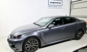 Szary Lexus IS F w garażu, z logo "pmgmotopl" na ścianie.