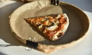 Jeden kawałek pysznej pizzy z pieczarkami na brązowym papierze. Zastanawiasz się, ile kawałków ma pizza?